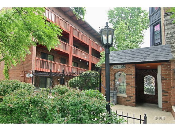 Front view of a multi-story brick building with balconies and entrance.