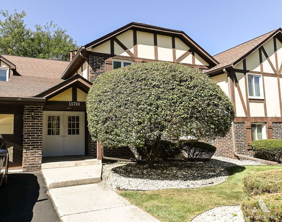 Front view of a two-story house with a gable roof and brick facade.