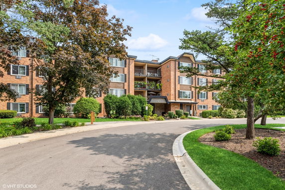 Front view of a multi-story brick apartment building with balconies.