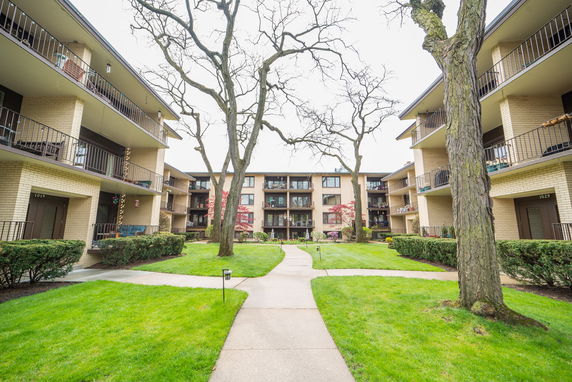Front view of apartment buildings with balconies and landscaped courtyard.