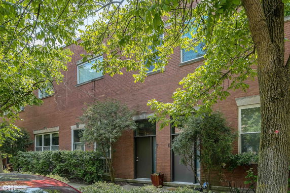 Front view of a brick two-story building with large windows and greenery.