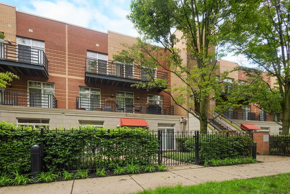 Front view of a multi-story brick building with balconies and a gated entrance.