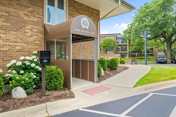 Entrance area of a condominium building with a covered entry and signage.