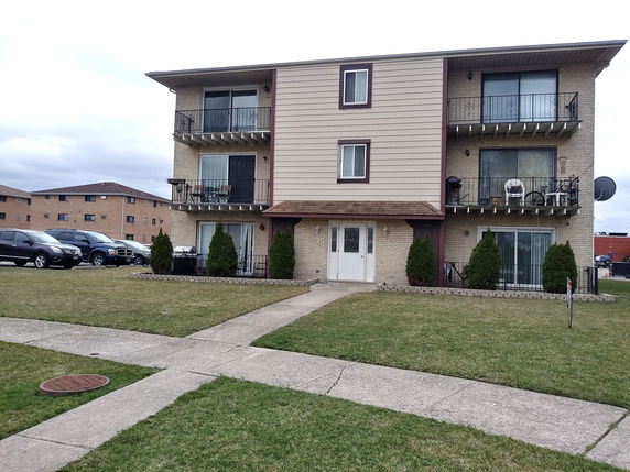 Front view of a three-story apartment building with balconies.
