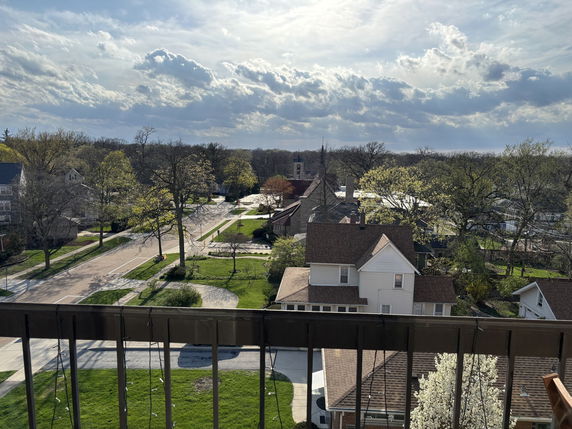 Panoramic view of a residential neighborhood with several houses and trees from a balcony.