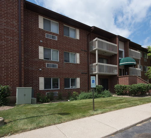 Front view of a three-story brick apartment building with balconies.