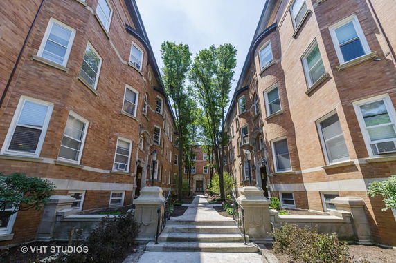 Front view of two brick apartment buildings with multiple windows and an entry path.