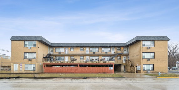 Front view of a three-story apartment building with balconies and an exterior staircase.