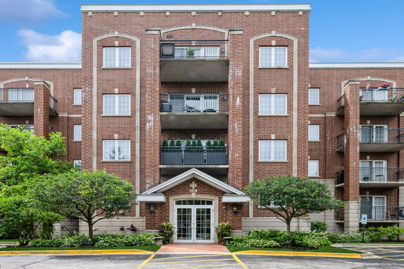 Front view of a multi-story brick building with balconies and a central entrance.