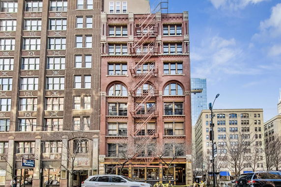 Front view of a multi-story building with brick exterior and fire escape.