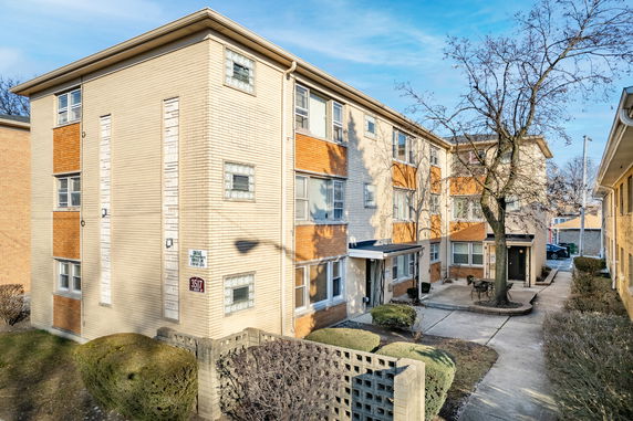 Front view of a multi-story residential building with brick facade and multiple windows.