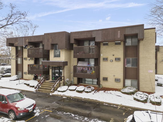 Front view of a three-story apartment building with brick exterior and balconies.