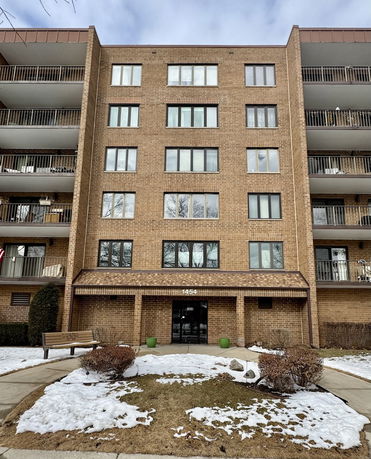 Front view of a multi-story brick building with a central entrance and balconies on either side.