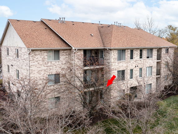 Front view of a multi-story brick apartment building with a pitched roof.