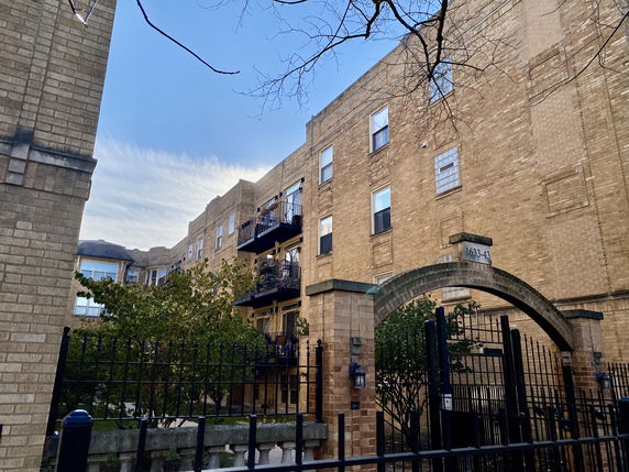 Front view of a multi-story brick apartment building with balconies.