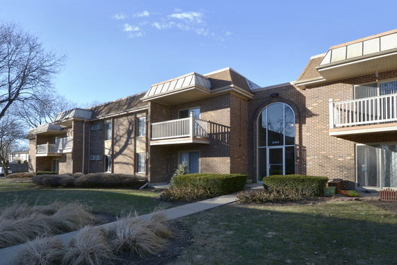 Front view of a multi-story brick apartment building with balconies.