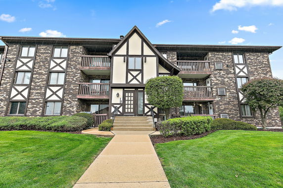 Front view of a multi-story apartment building with brick and timber facade.