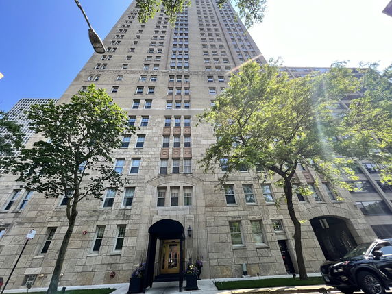 Front view of a tall residential building with numerous windows and a stone facade.