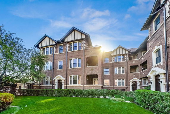 Front view of a multi-story brick building with gabled roofs and multiple windows.