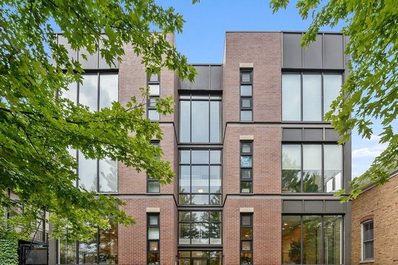 Front view of a modern multi-story building with large windows and brick facade.