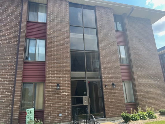 Front view of a multi-story brick apartment building with large windows.