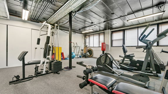 Indoor gym area with exercise equipment including a treadmill, stationary bike, and weight machine.