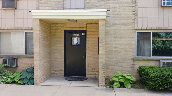 Front view of a building entrance with a covered doorway and brick exterior.