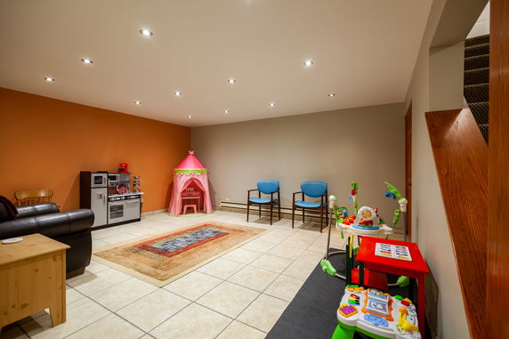 Indoor play area with toys and seating in a basement room.