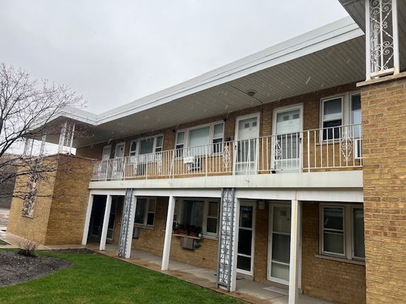 Front view of a two-story apartment building with a balcony and brick exterior.