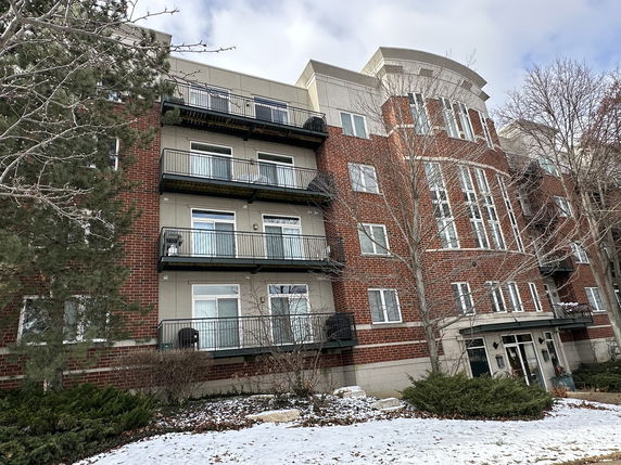 Front view of a multi-story brick apartment building with balconies and large windows.