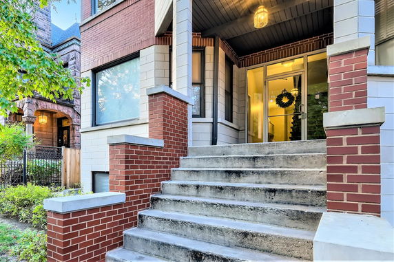Front view of a brick house with a staircase leading to the entrance.