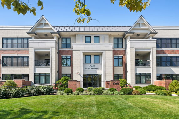 Front view of a multi-story apartment building with balconies and a central entrance.