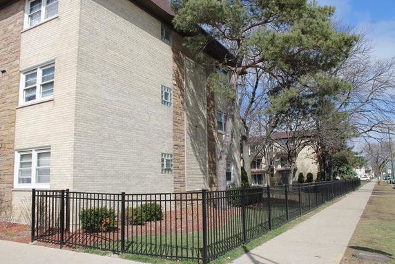 Front view of a multi-story brick building with a fenced yard.