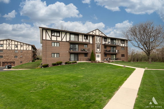Front view of a multi-story condominium building with brick and white panel exterior.