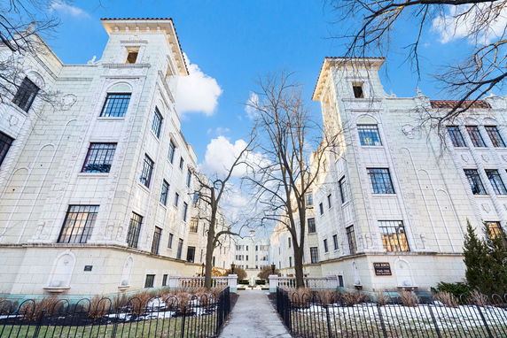 Front view of a multi-story building with white facade and large windows.