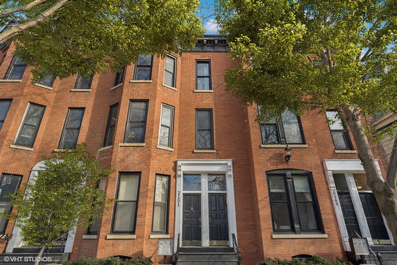 Front view of a multi-story brick building with large windows and black doors.