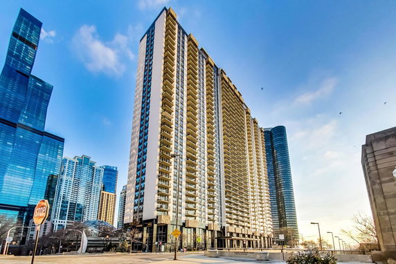 Front view of a tall residential building with multiple balconies in an urban area.