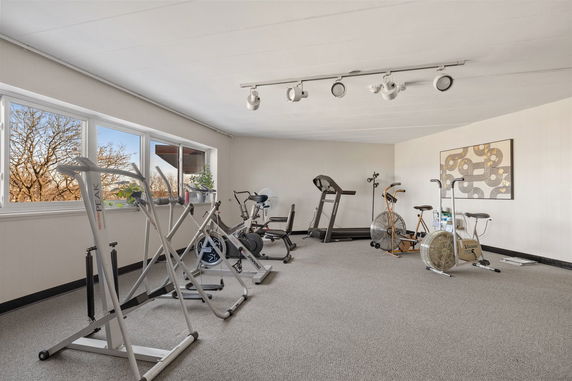Room with various exercise equipment including stationary bikes and a treadmill.