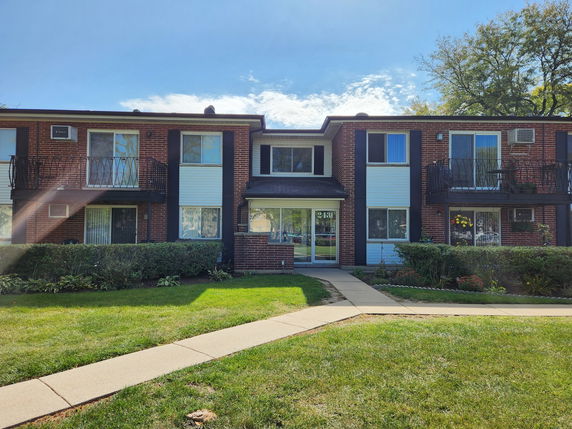 Front view of a two-story brick apartment building with balconies.