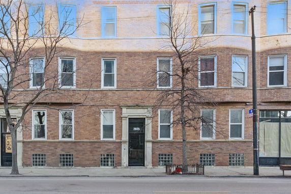 Front view of a multi-story brick building with multiple windows.