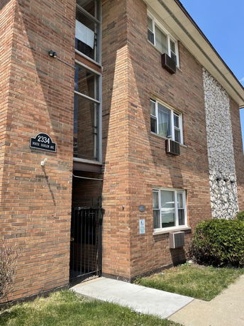 Front view of a multi-story brick building with windows and an entrance gate.