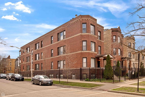 Front view of a multi-story brick apartment building on a city street.
