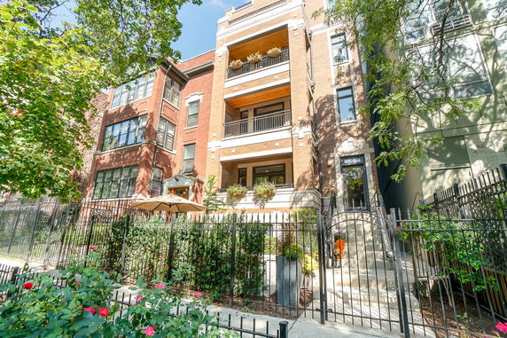 Front view of a multi-story residential building with balconies and a gated entrance.