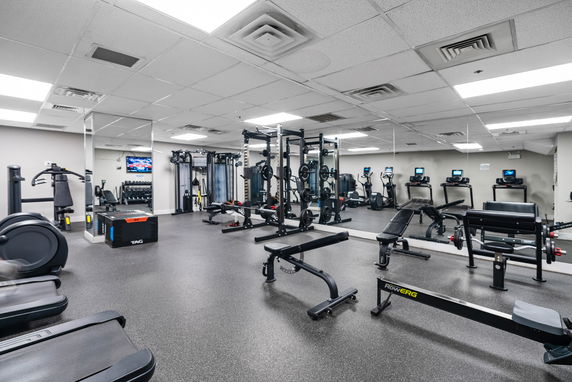 Indoor gym area with various exercise equipment and mirrors.