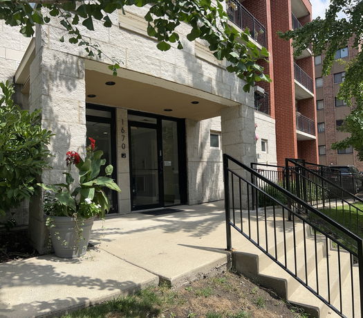 Front view of a multi-story building entrance with stone and brick facade.