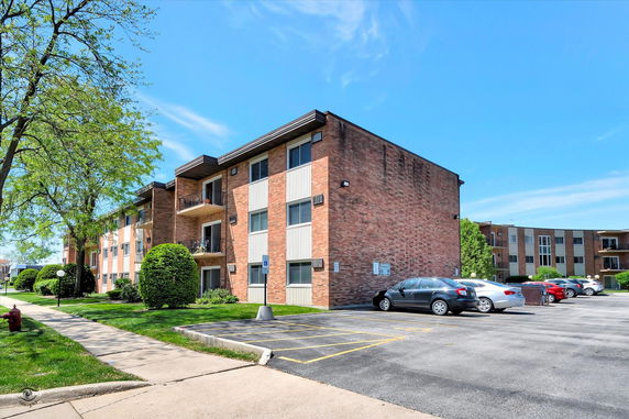 Front view of a three-story brick apartment building with balconies.