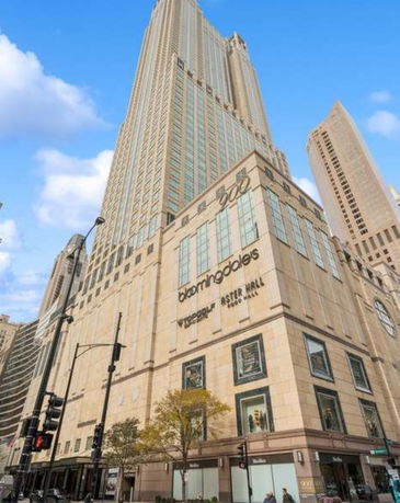 Front view of a tall commercial building with large windows and retail signage.
