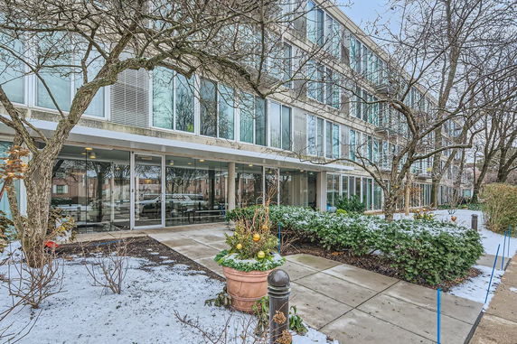 Front view of a multi-story building with large windows and a snowy entrance path.