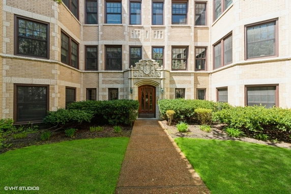 Front view of a multi-story building with decorative entrance and surrounding greenery.