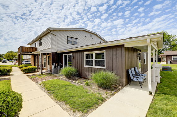 Front view of a two-story house with a covered porch and brown siding.